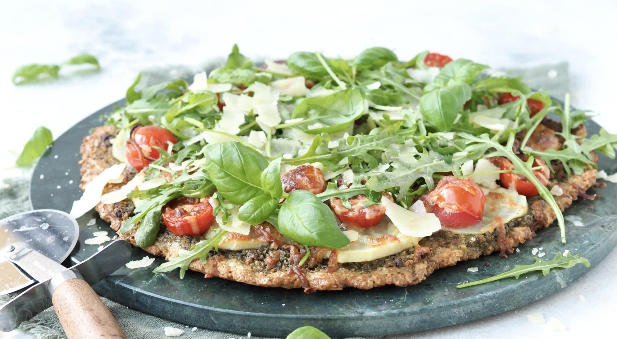 En glutenfri vegetar pizza med rucola, pesto, tomater, parmesan