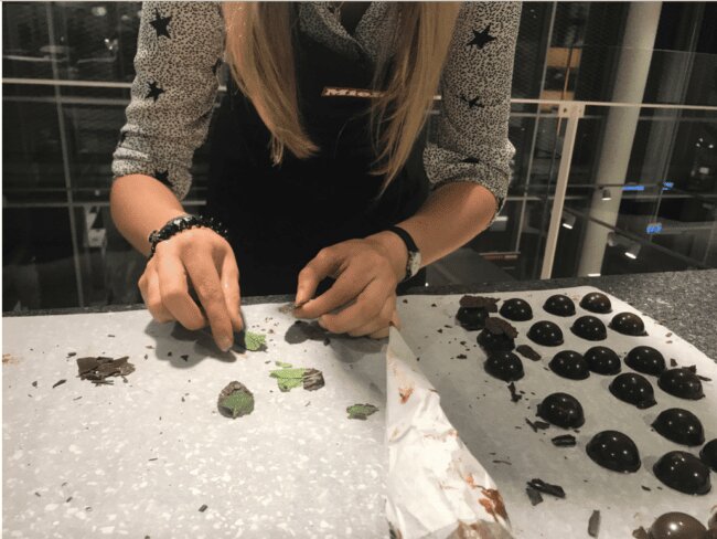 En dame står og piller chokolade af mynteblade